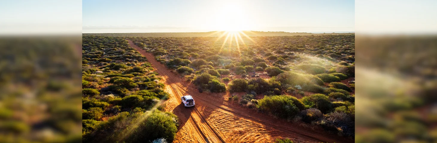 A 4x4 driving through Western Australia at sunset.