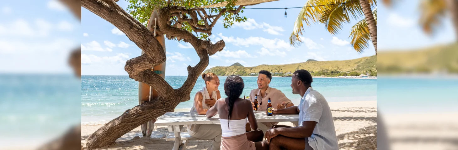 Four people drinking Carib beers on a beach in St. Kitts